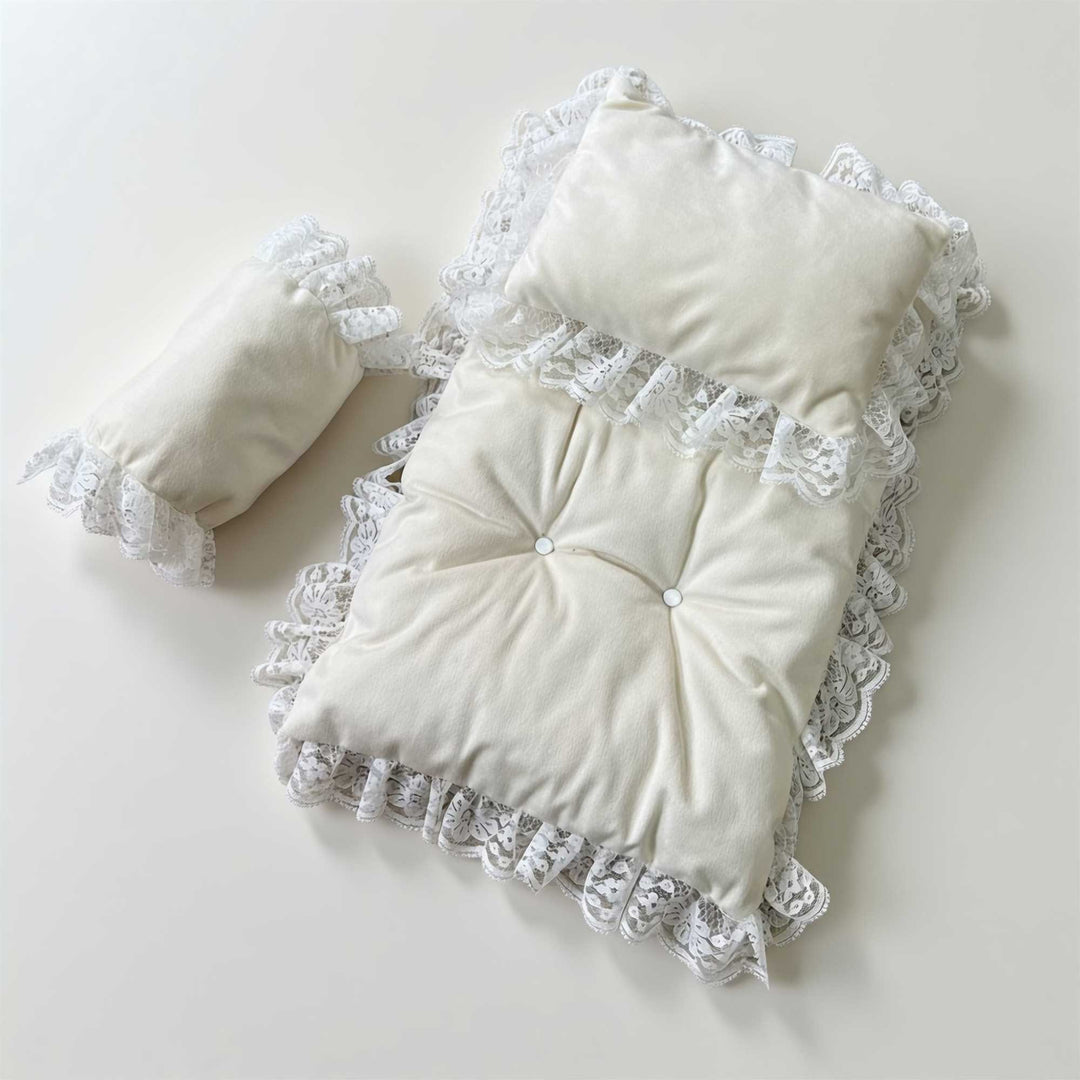 A 3-piece set featuring a tufted pearl white rug and pillows with lace trim for newborn photography.
