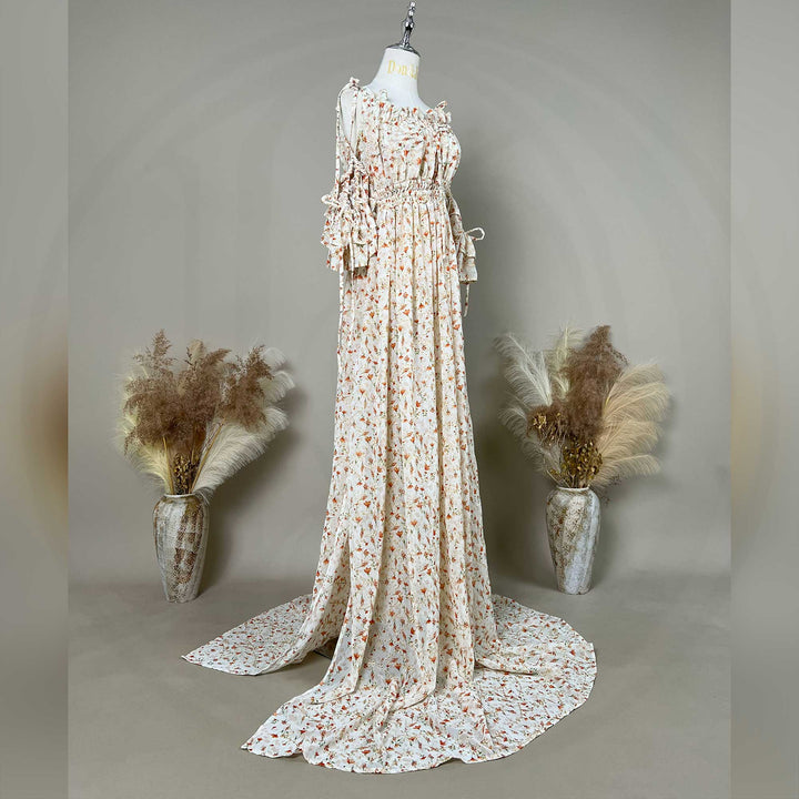 A side view of a mannequin displays an Alke floral off-shoulder gown with a train.