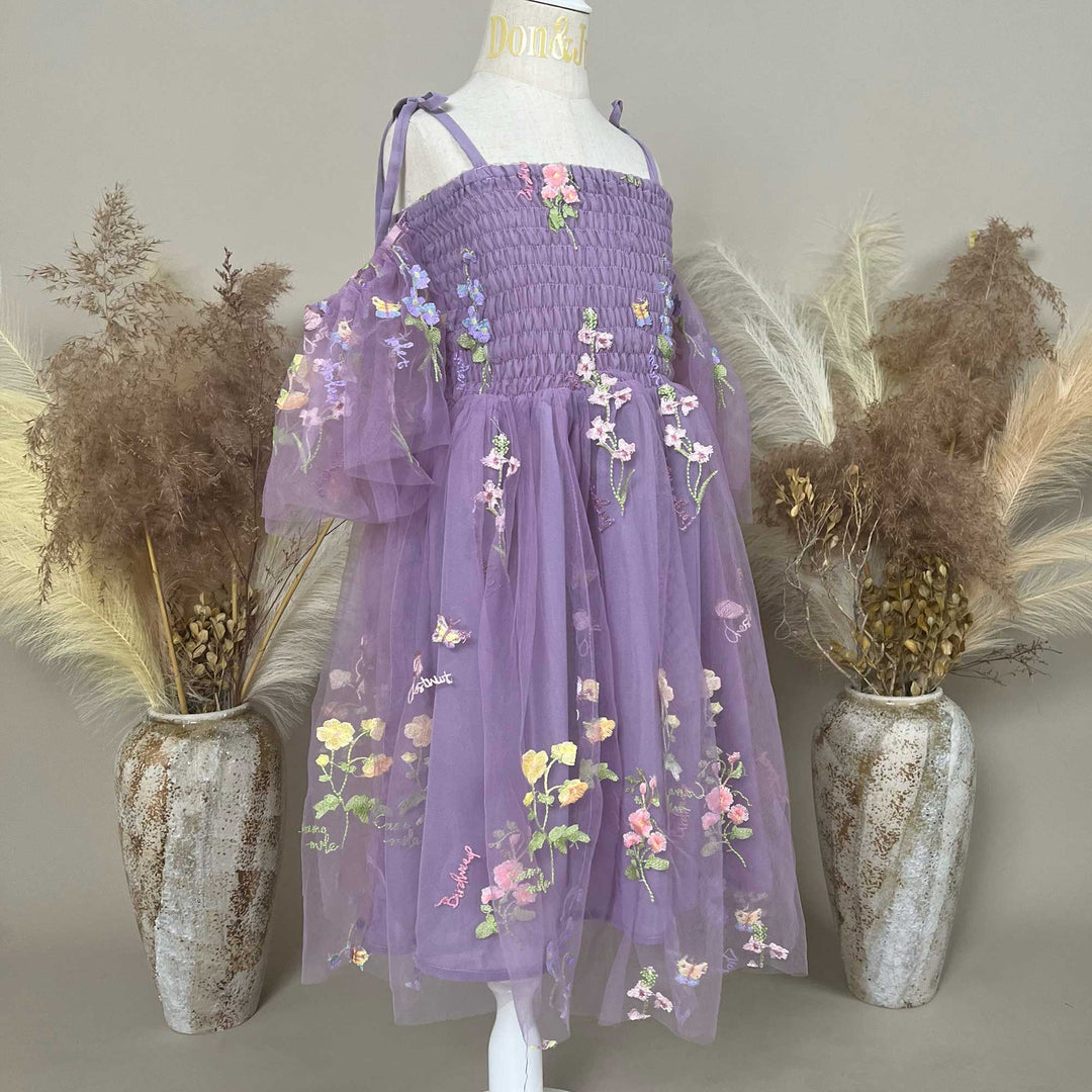 A side view of mannequin displays an Ananke purple floral embroidered dress