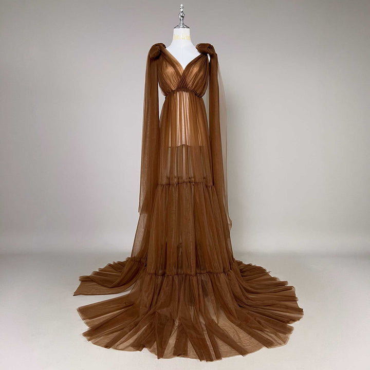 A Acaste gown is displayed on a mannequin against a white wall; the dress features a V-neck, shoulder ties, and a tiered skirt structure.
