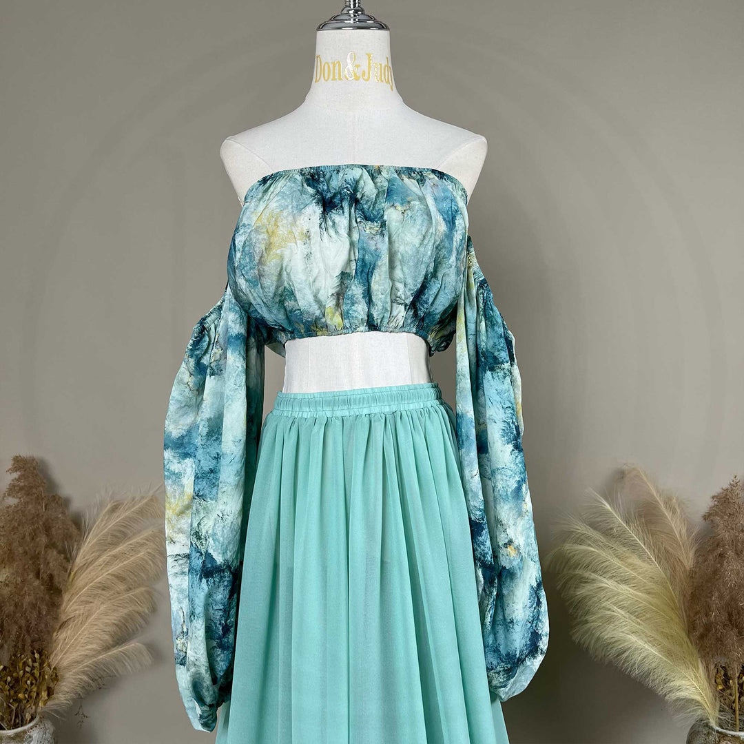 A Alala tie dye printed off shoulder top and a mint skirt with a train are displayed on a mannequin. 