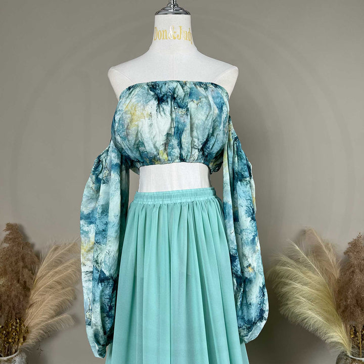 A Alala tie dye printed off shoulder top and a mint skirt with a train are displayed on a mannequin. 