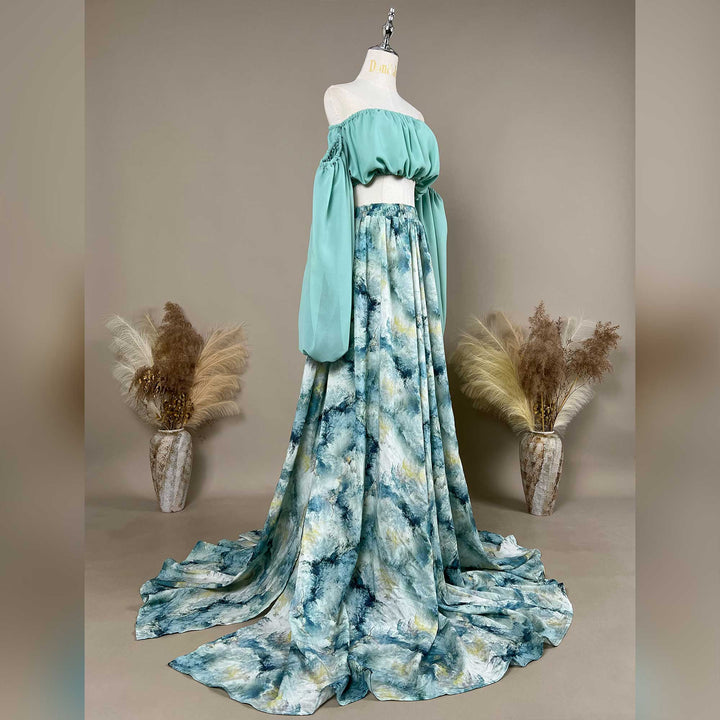 A side view of a Alala mint off shoulder top and a tie dye printed maxi skirt with a train are displayed on a mannequin. 