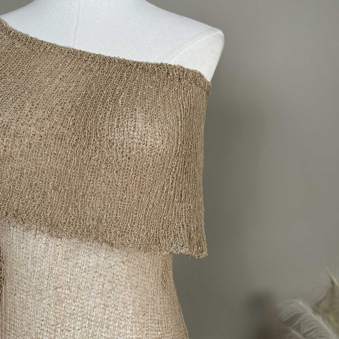 A Close up of a mannequin displays an Aletheia  camel off-shoulder neckline of a knitted fabric.