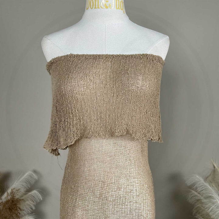 A close up of a mannequin displays an Aletheia camel off-shoulder neckline of a knitted fabric.