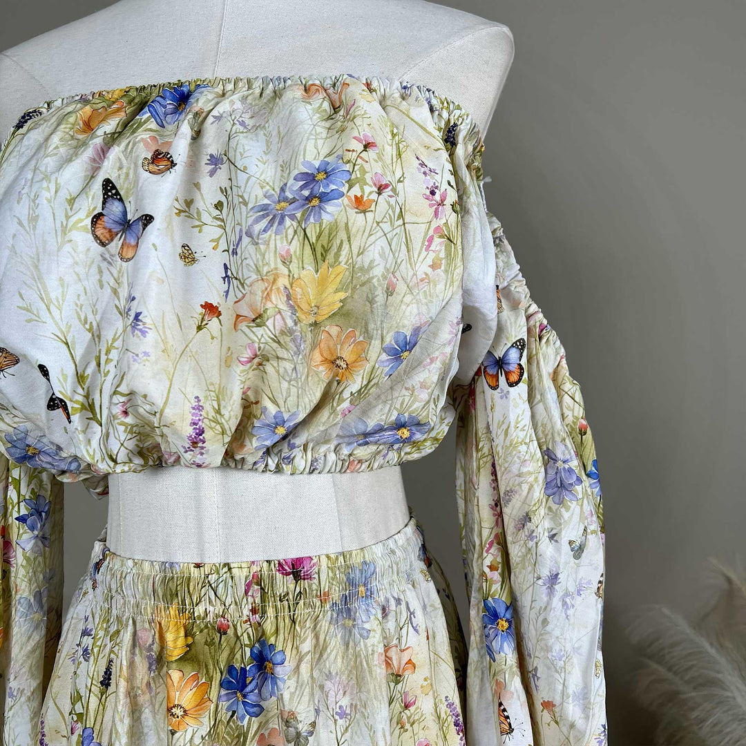 Close up of an Aphaea floral and butterfly print off-shoulder two-piece is displayed on a mannequin.