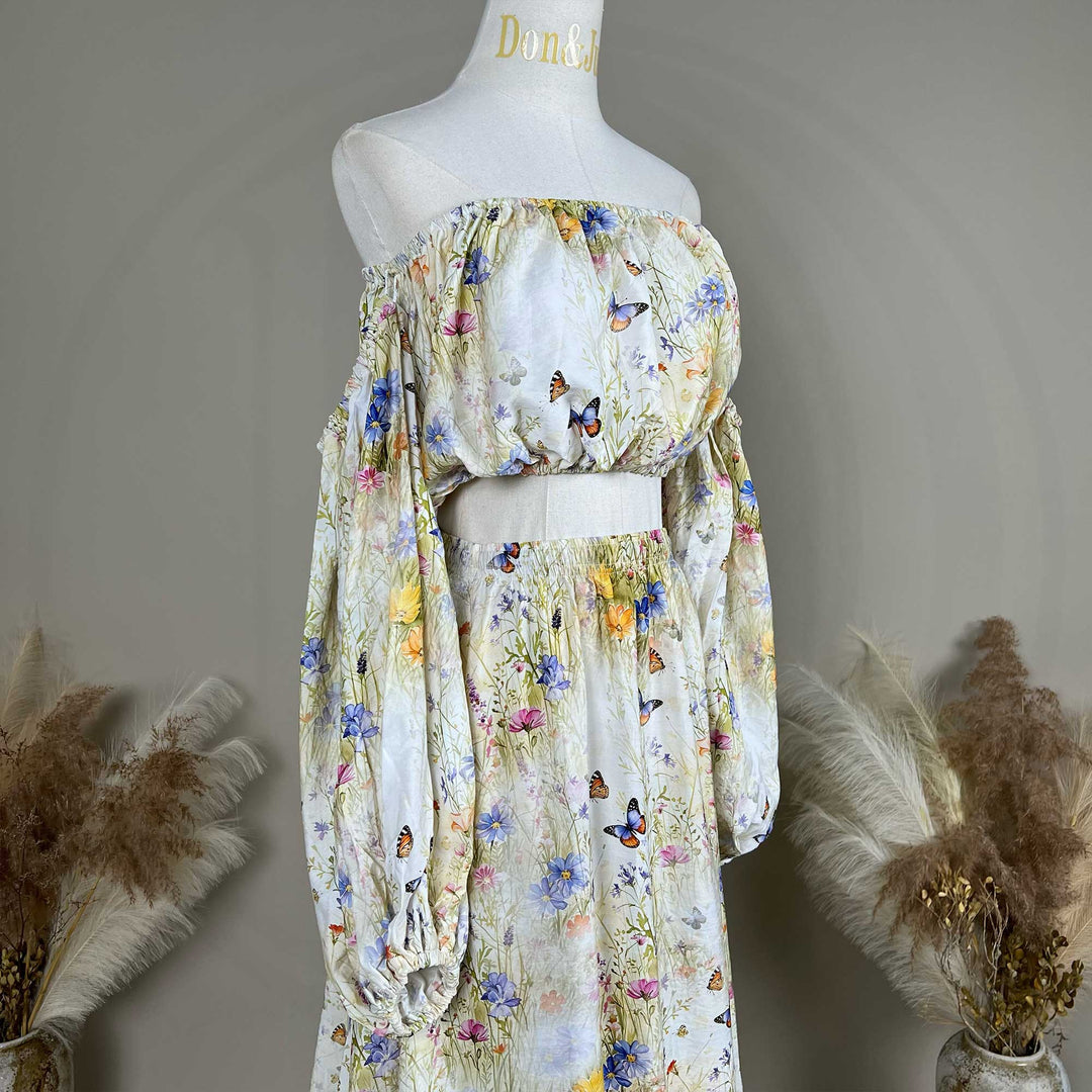 A side view of an Aphaea floral and butterfly print off-shoulder two-piece is displayed on a mannequin.