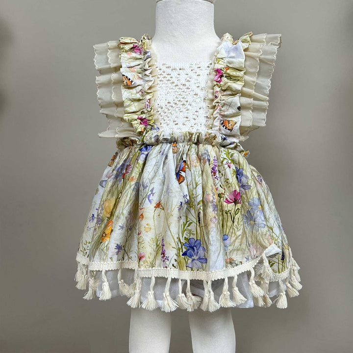 An Arachne floral tassel dress hangs on a mannequin.