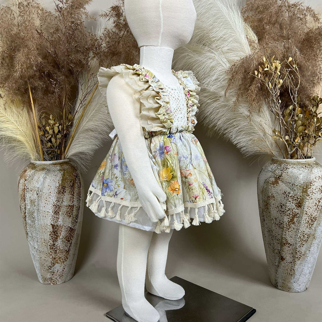 A side view of an Arachne floral tassel dress hangs on a mannequin.
