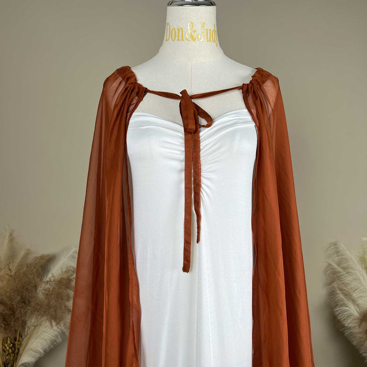 A close up of Astraea satin maxi cape maternity dress with a terracotta chiffon cape is displayed on a mannequin.