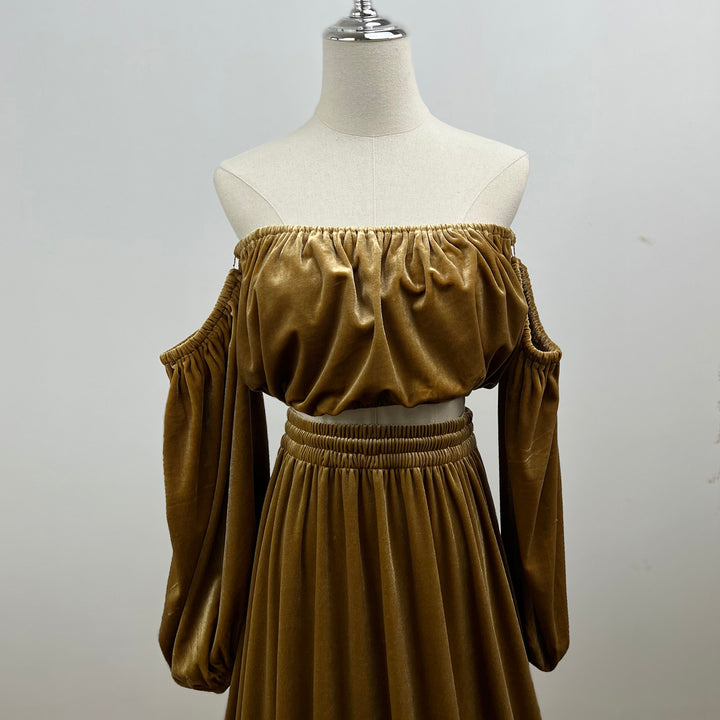 A mannequin displays a close-up of Belisama dress velvet off-shoulder top and floor-length skirt. The two-piece outfit has a ruffled skirt hem.