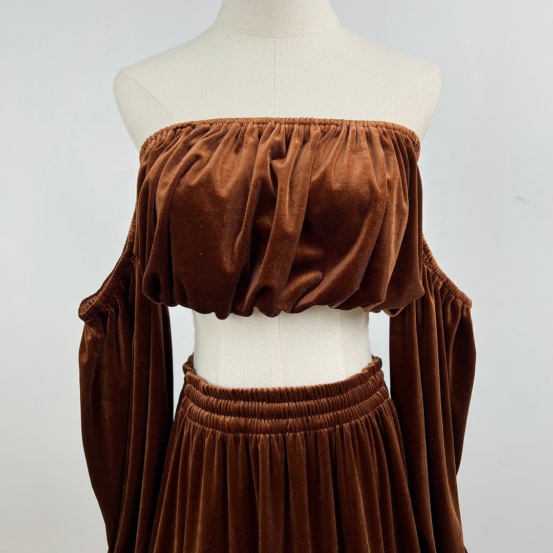 A mannequin displays a close-up of Belisama dress velvet off-shoulder top and floor-length skirt. The two-piece outfit has a ruffled skirt hem.