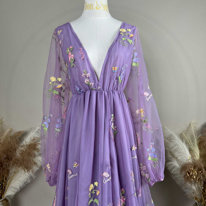A Dike purple tulle long-sleeve floral embroidered gown with a train is displayed on a mannequin.