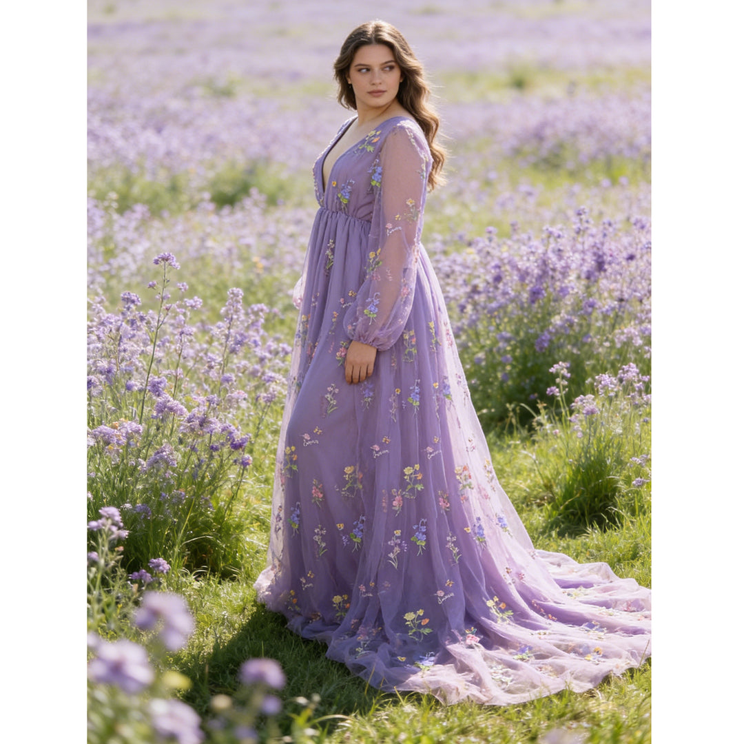 A woman stands in a flower field wearing a Dike purple V-neck tulle floral embroidered gown. 