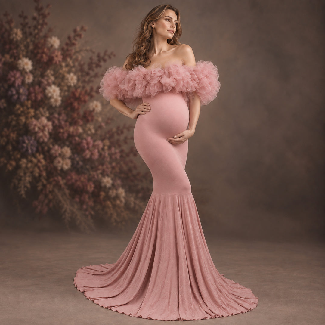 A pregnant woman models a dusty pink off-the-shoulder maternity gown with a ruffled tulle bodice and a long pleated skirt