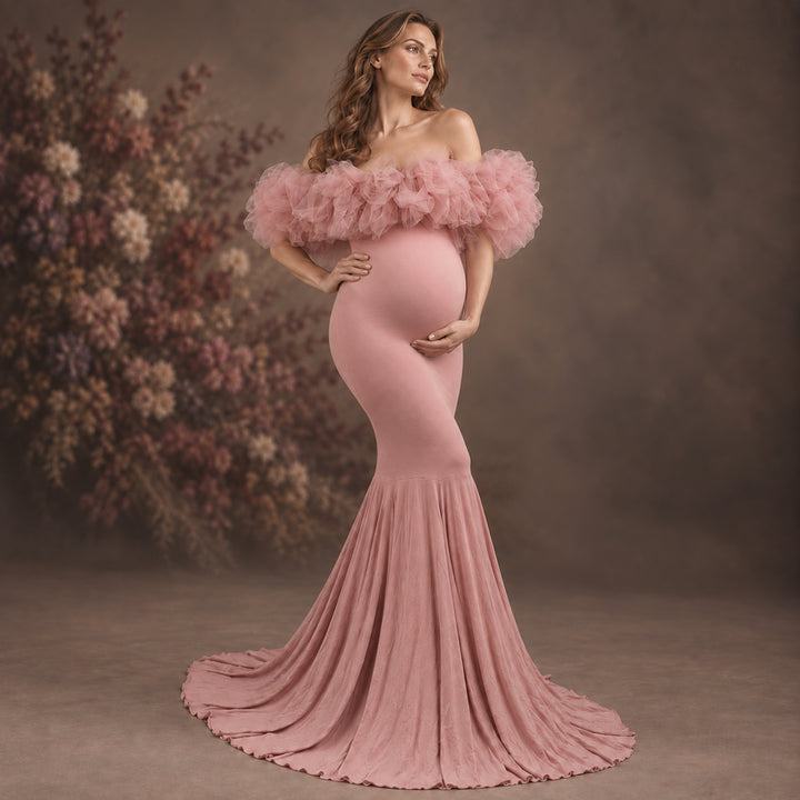 A pregnant woman models a dusty pink off-the-shoulder maternity gown with a ruffled tulle bodice and a long pleated skirt