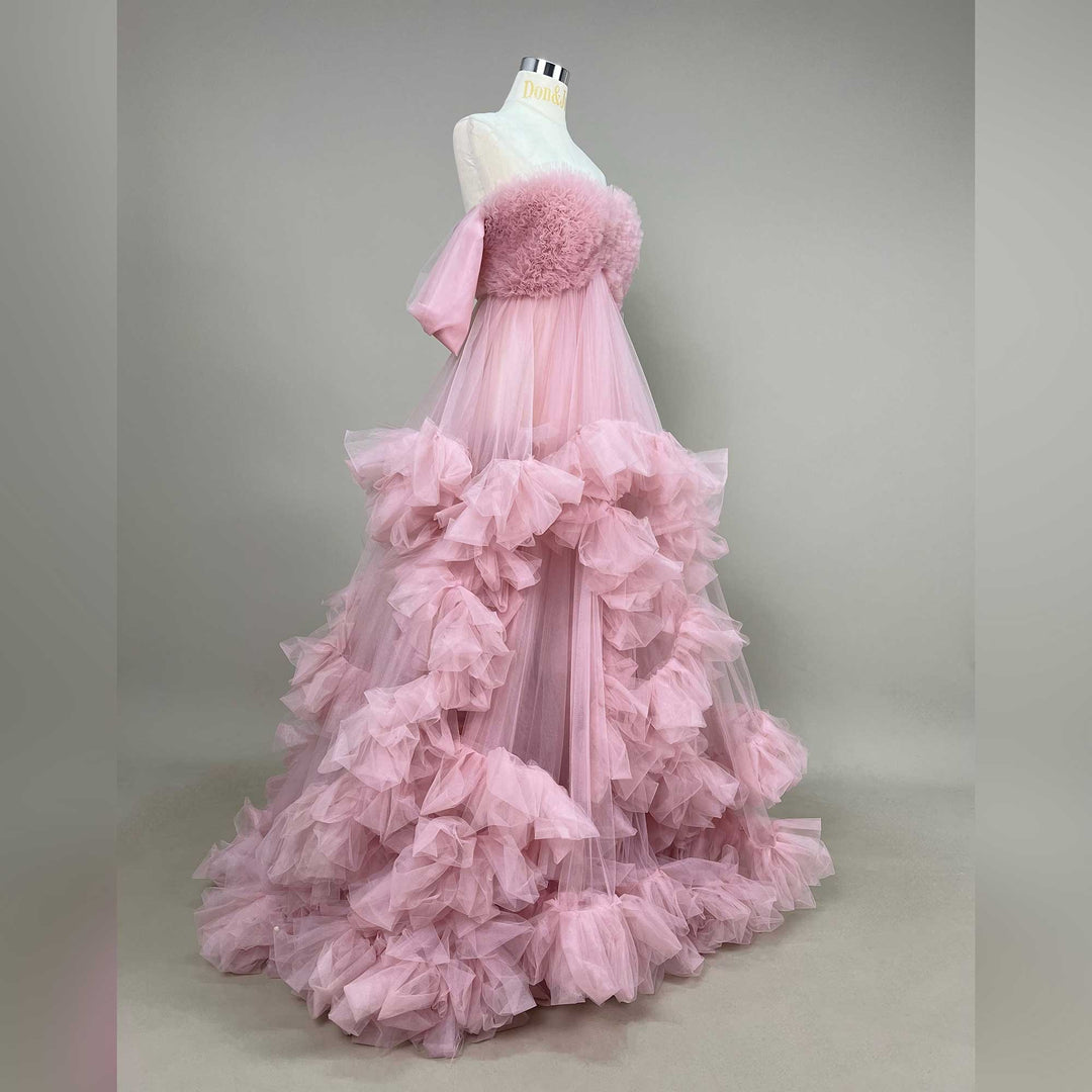 A mannequin displays a Electra pink strapless ruffled tulle gown; the dress features multi-layered ruffles and a train.