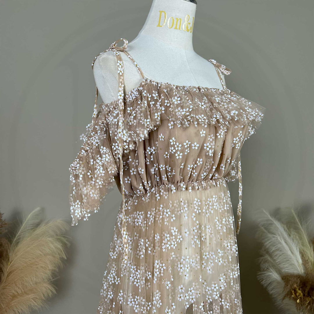 A khaki tulle dress with white floral embroidery and tie-shoulder straps, displayed on a mannequin.