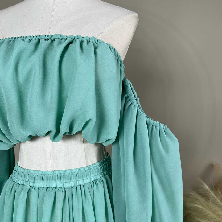 A gaia mint flowy chiffon off-shoulder maternity top with long sleeves displayed on a mannequin.