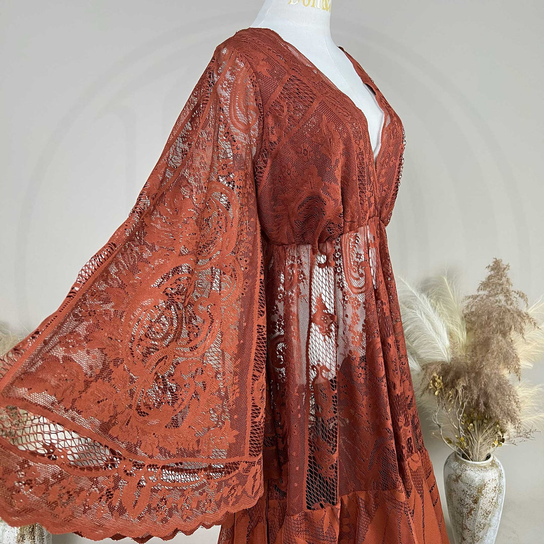 A Terracotta, harpocrates dress with tiered ruffle lace details is displayed on a mannequin against a neutral gray background.