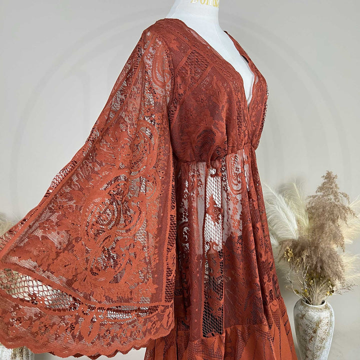 A Terracotta, harpocrates dress with tiered ruffle lace details is displayed on a mannequin against a neutral gray background.