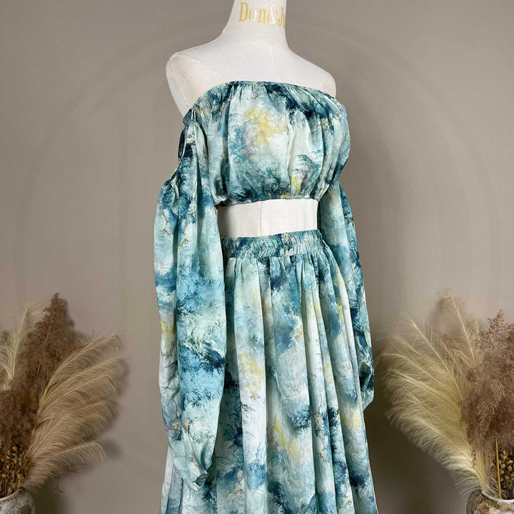 A close up of Hestia tie dye print off-shoulder top and long skirt with a train are displayed on a mannequin. 