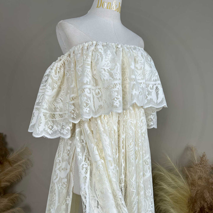 A mannequin displays a side view of a beige off-shoulder lace gown with ruffled sleeves and a train