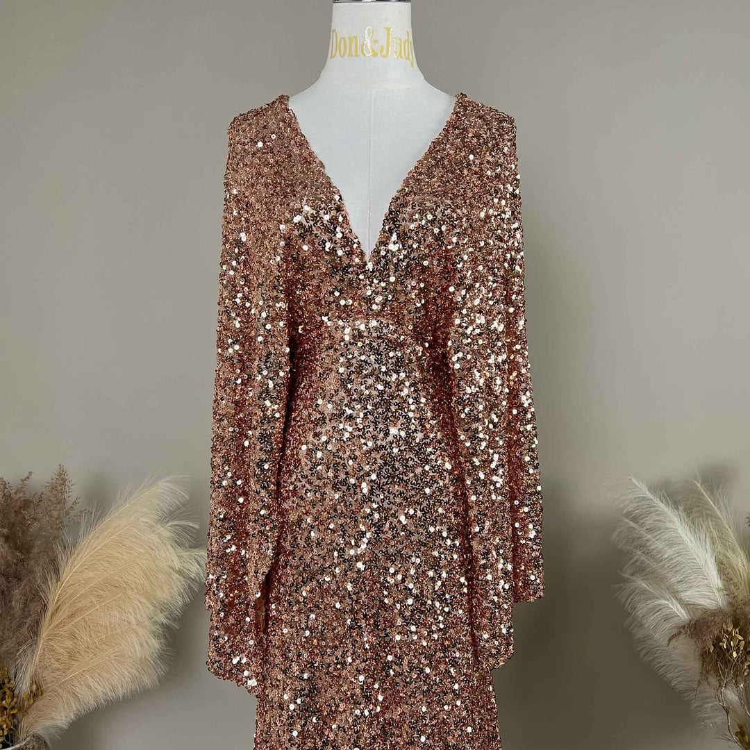 A pink gold Mara dress sequined gown, featuring a V-neck and flared sleeves displayed on a mannequin.