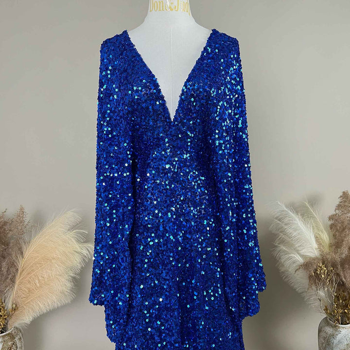A sapphire blue Mara sequined gown is displayed on a mannequin, featuring a V-neck and flared sleeves. 