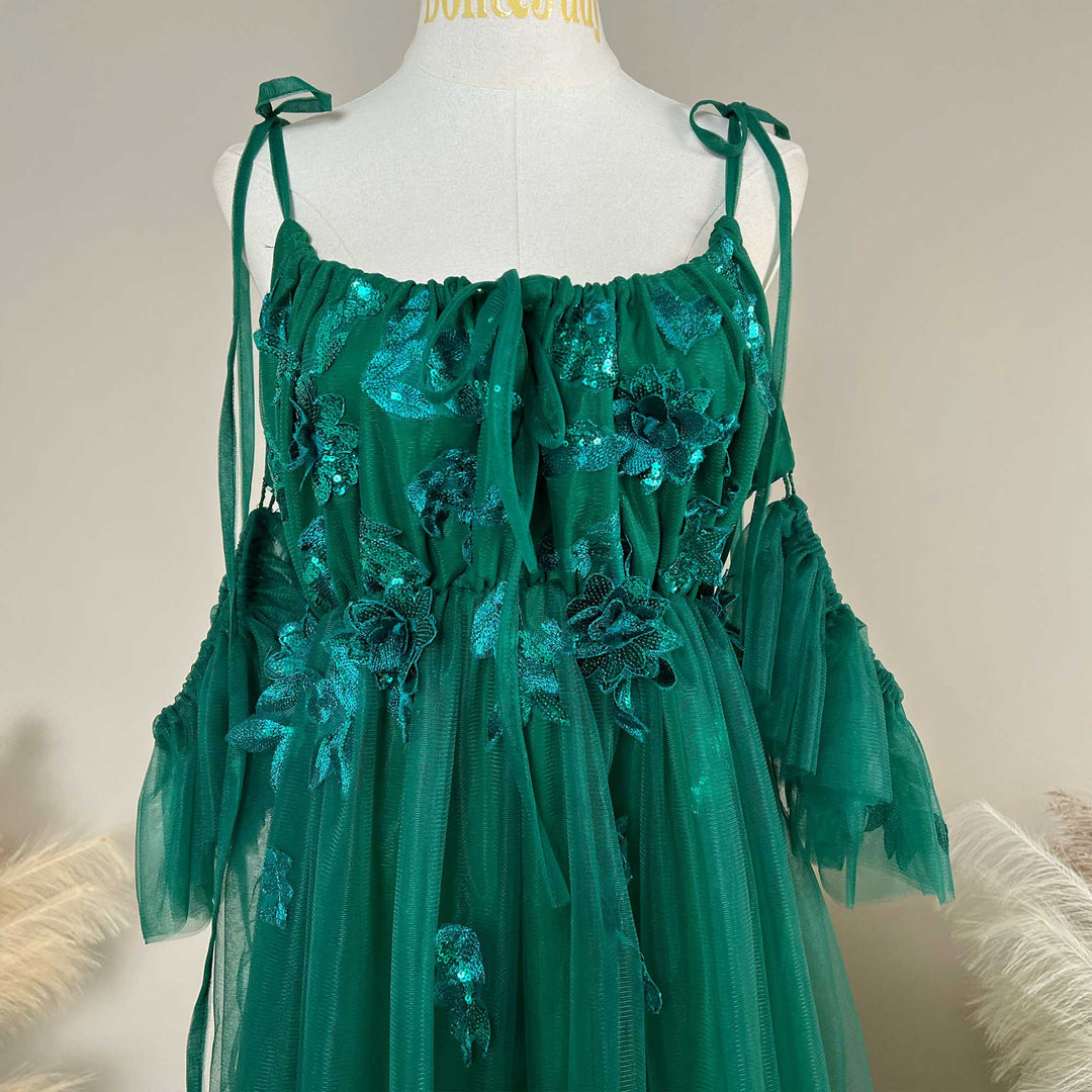Close-up detail of a Oreades green floral embroidered off-shoulder tiered ruffle maternity photography dress.