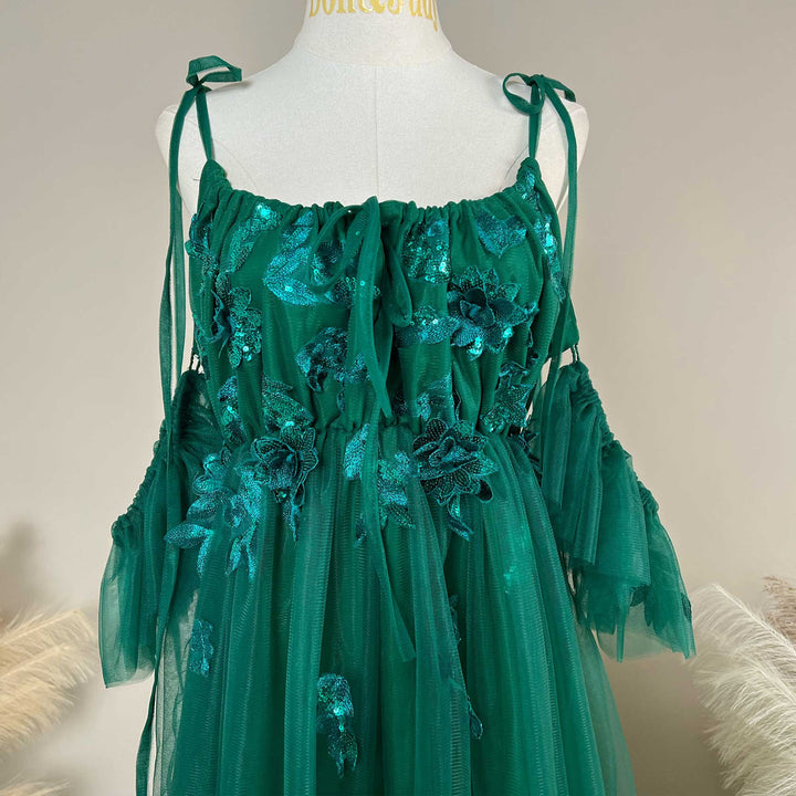 Close-up detail of a Oreades green floral embroidered off-shoulder tiered ruffle maternity photography dress.