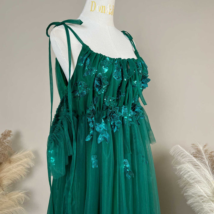 Close-up detail of a Oreades green floral embroidered off-shoulder tiered ruffle maternity photography dress, highlighting the front neckline and gathered waist design details.