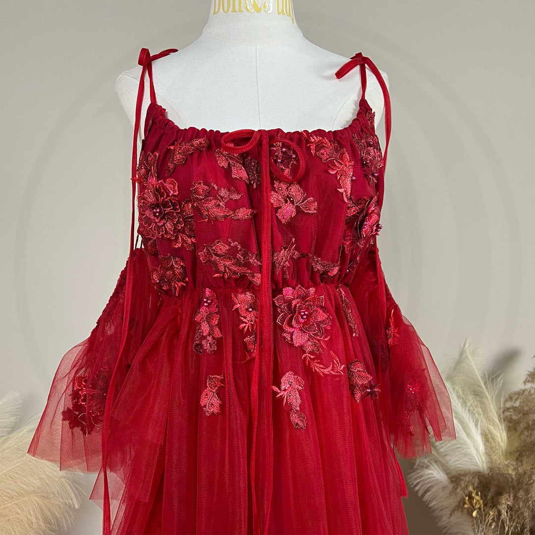 Close-up detail of a Oreades red floral embroidered off-shoulder tiered ruffle maternity photography dress.