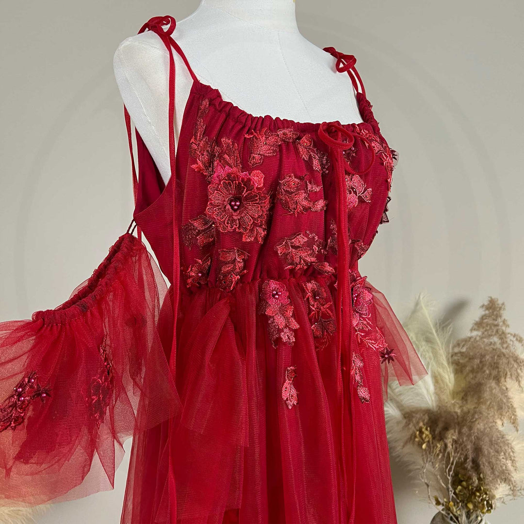 Close-up detail of a Oreades red floral embroidered off-shoulder tiered ruffle maternity photography dress, highlighting the front neckline and gathered waist design details.