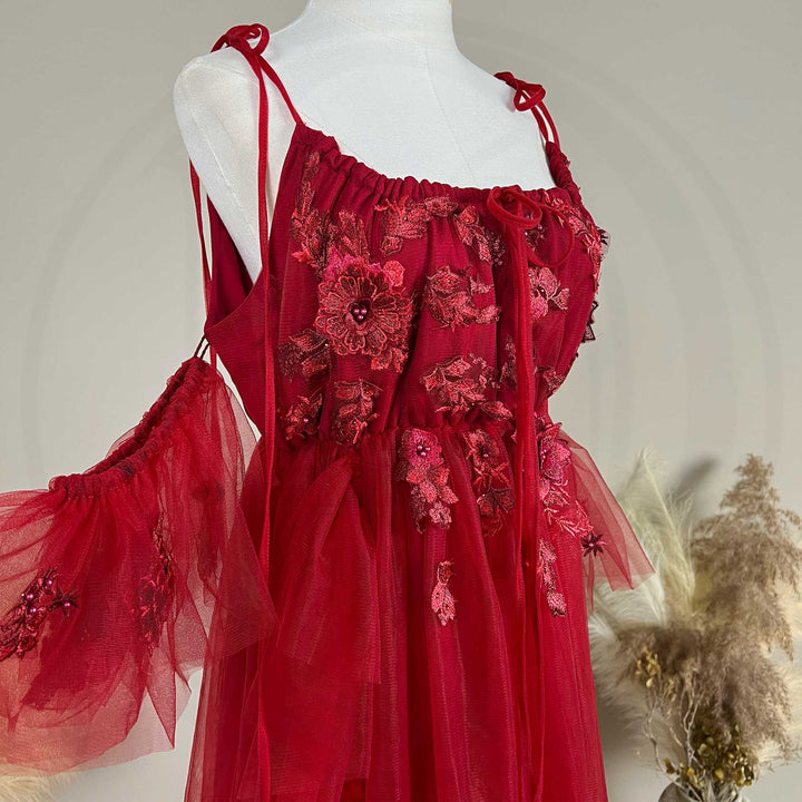 Close-up detail of a Oreades red floral embroidered off-shoulder tiered ruffle maternity photography dress, highlighting the front neckline and gathered waist design details.
