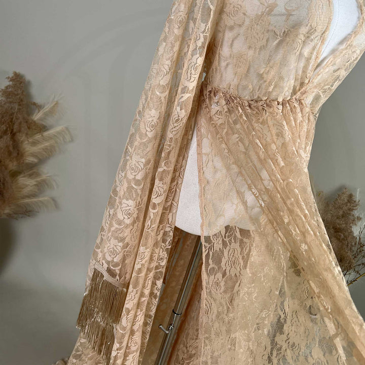 A khaki lace gown is displayed on a mannequin, featuring rose patterns, a ruched high waistline, and fringe cuffs.