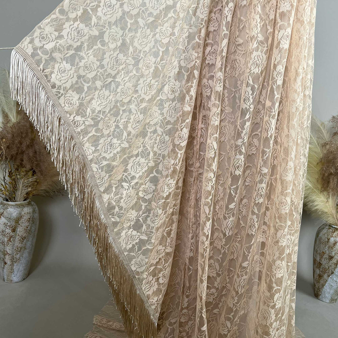 Khaki rose lace fabric is displayed hanging, featuring dense floral textures and fringe trim along the edge.