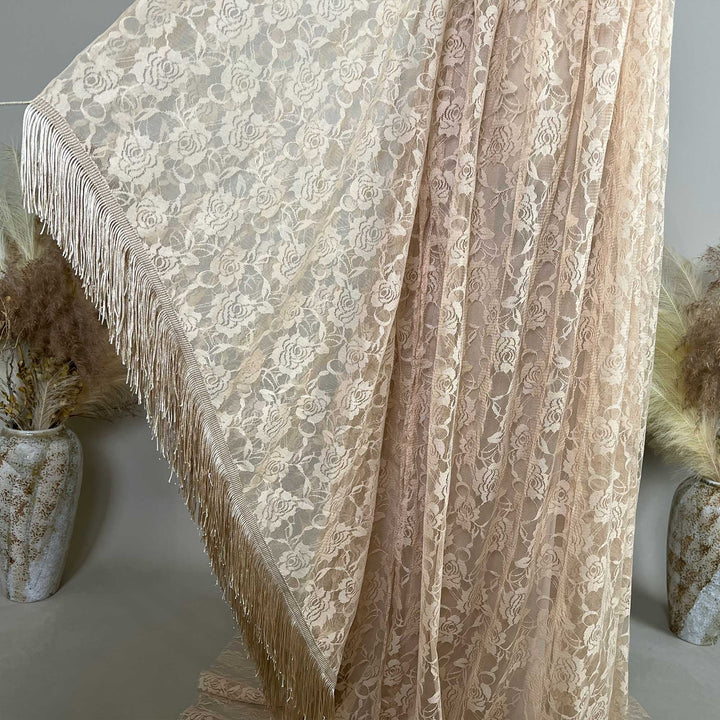 Khaki rose lace fabric is displayed hanging, featuring dense floral textures and fringe trim along the edge.