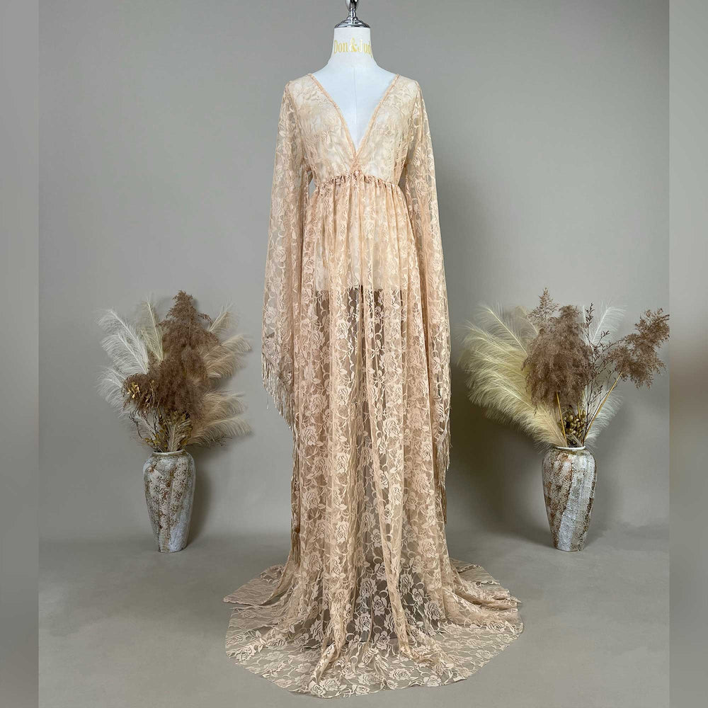 A khaki lace V-neck gown is displayed on a mannequin, featuring a ruched high waistline, fringe cuffs, and a floor-sweeping skirt.