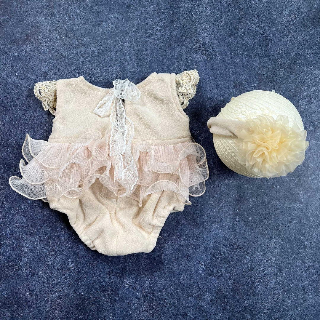 On the left is a skin polar fleece romper, shown from the back, On the right sits a headband adorned with a large organza flower on the side.