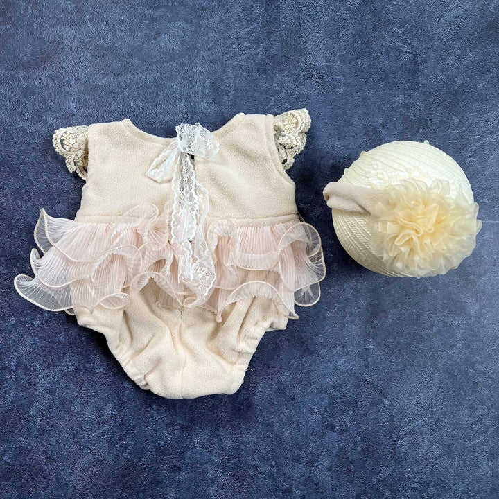 On the left is a skin polar fleece romper, shown from the back, On the right sits a headband adorned with a large organza flower on the side.