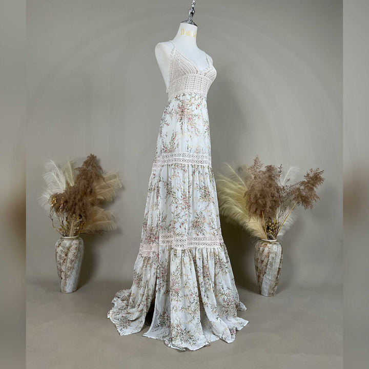 The Urania,an apricot bottom floral maternity maxi dress with spaghetti straps, a crochet bodice, and lace-trimmed tiered panels on the skirt, displayed on a mannequin.