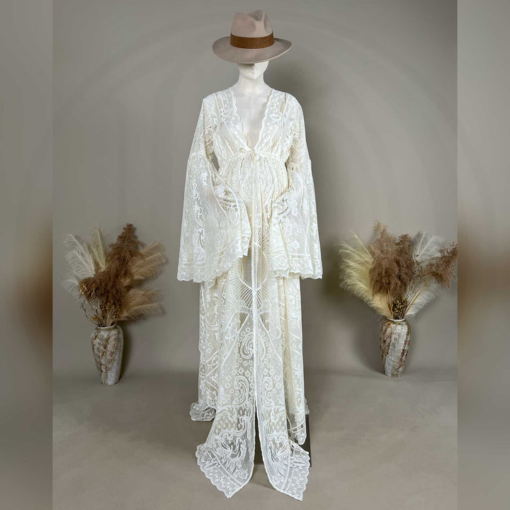 A beige lace ,Zephyra dress with long bell sleeves and a V-neckline, displayed on a mannequin. The robe features a tie waist, an open front, and a floor-length train with scalloped edges.